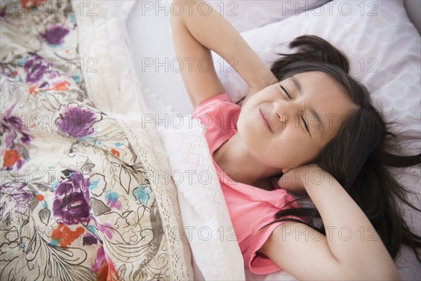Girl covering her ears in bed