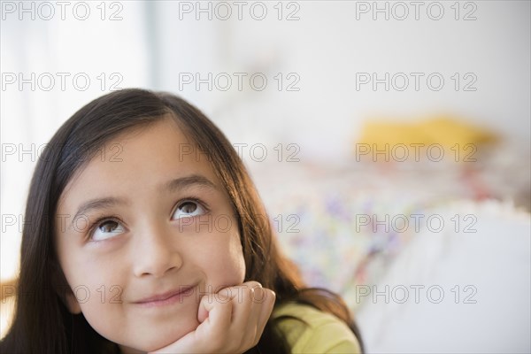 Smiling girl daydreaming with hand on chin