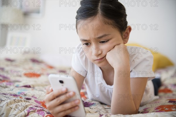 Frustrated girl using cell phone on bed