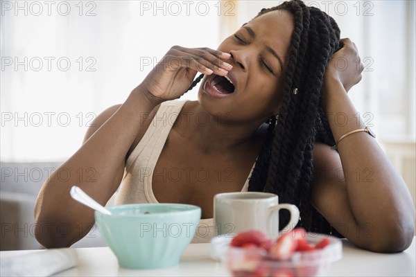 Black woman yawning at table