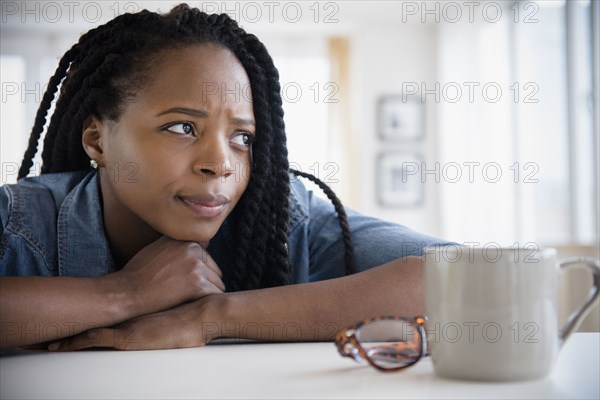 Anxious Black woman resting chin on hands