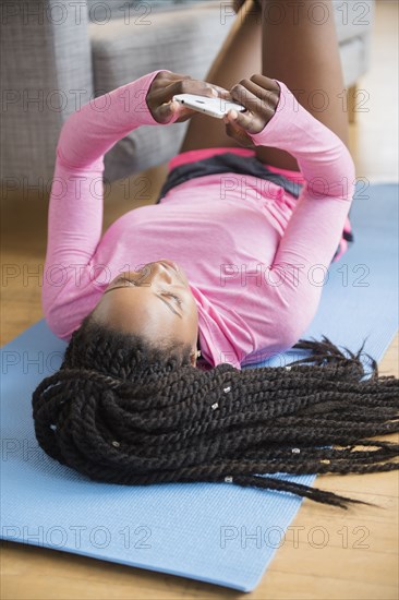 Black woman using cell phone on yoga mat