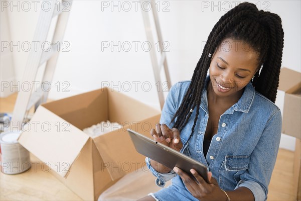 Black woman using digital tablet in new home