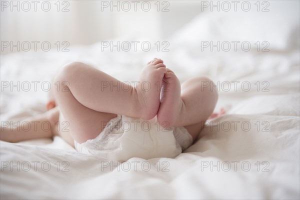 Legs of Caucasian baby girl laying on bed