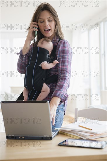 Mother working at home with new baby daughter