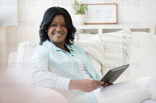 Black woman using digital tablet on sofa