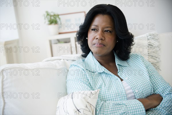 Unhappy Black woman sitting on sofa