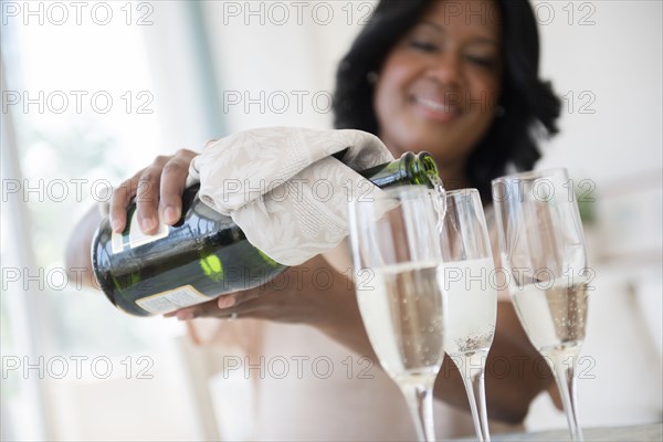 Black woman pouring glasses of champagne