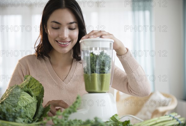 Hispanic woman blending healthy smoothie