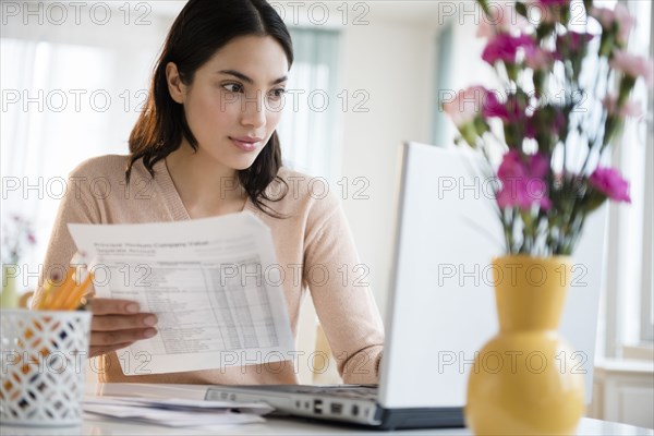 Hispanic woman paying bills on laptop