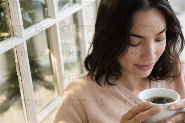 Hispanic woman drinking cup of coffee