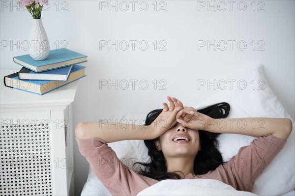 Hispanic woman waking up in bed