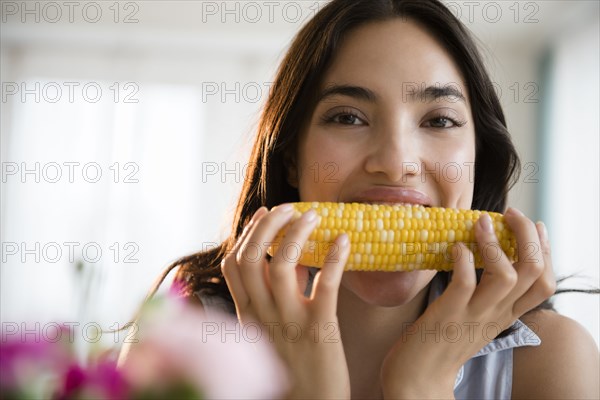 Hispanic woman eating corn on the cob