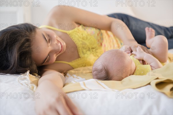 Mother playing with baby daughter on bed