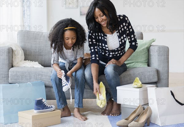 Mother and daughter trying on shoes on sofa
