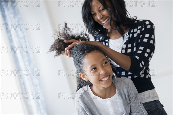 Mother styling hair of daughter