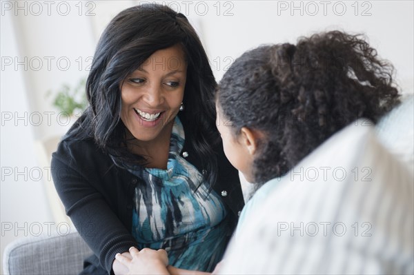 Mother and daughter talking on sofa