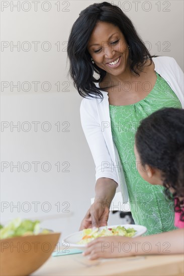 Mother serving daughter salad