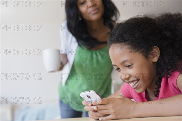 Mother watching daughter use cell phone