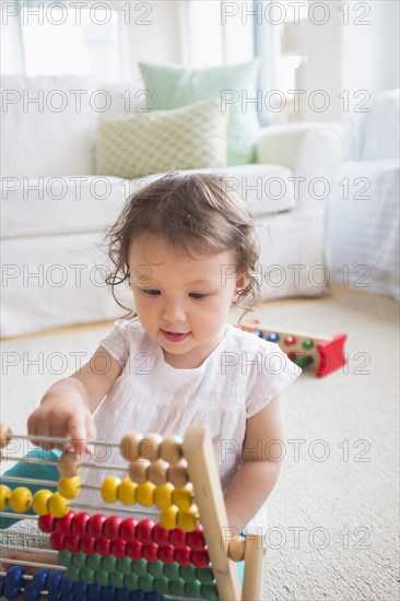 Mixed race baby girl playing with abacus