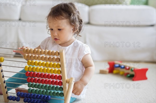 Mixed race baby girl playing with abacus