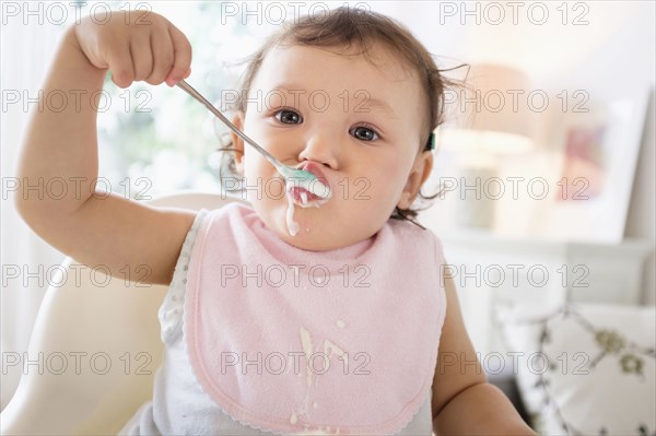 Mixed race baby girl eating yogurt
