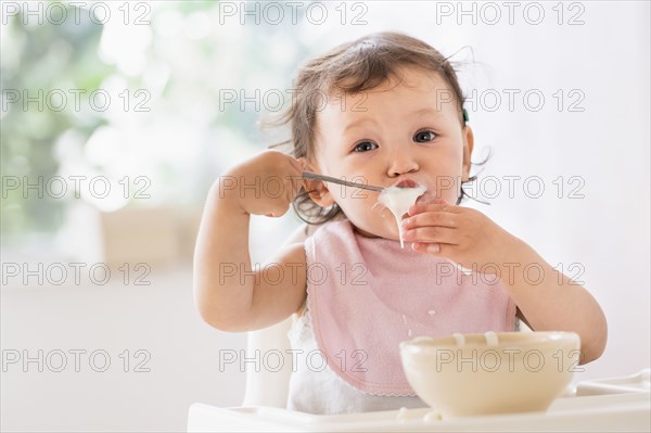 Mixed race baby girl eating yogurt