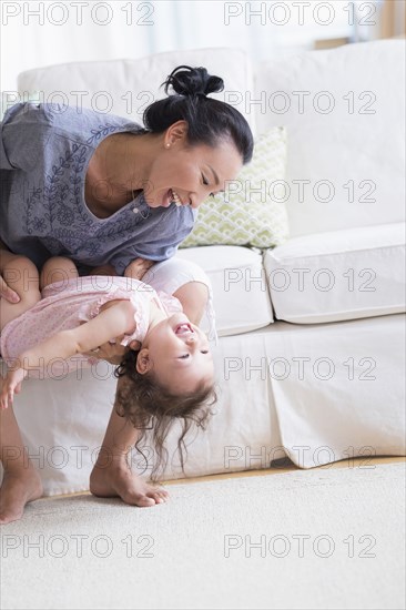 Mother and baby daughter playing on sofa