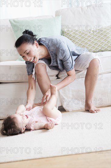 Mother and baby daughter playing in living room