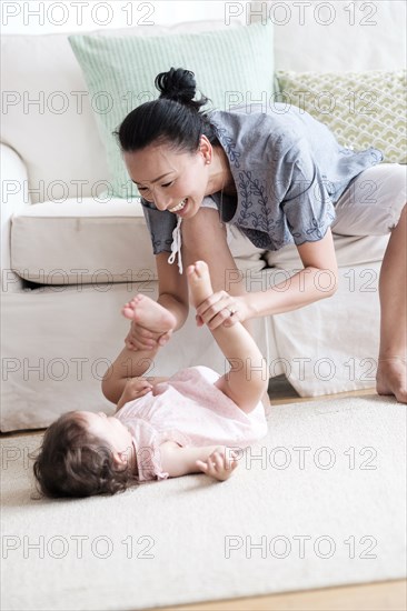 Mother and baby daughter playing in living room
