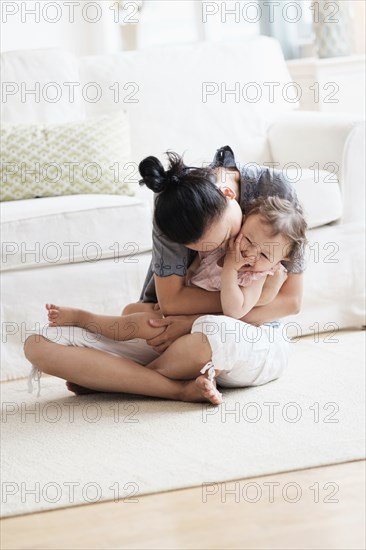 Mother and baby daughter playing in living room