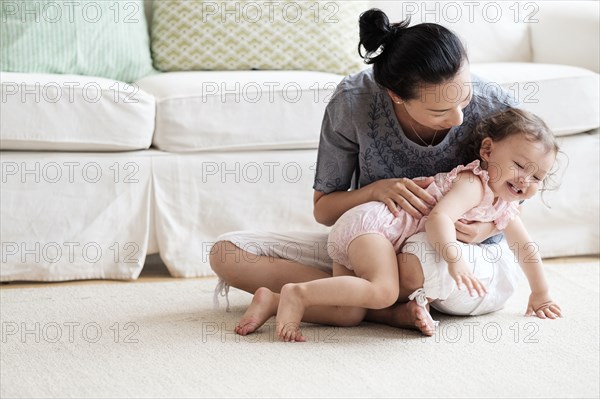 Mother and baby daughter playing in living room