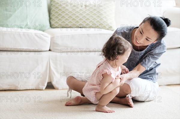 Mother and baby daughter playing in living room