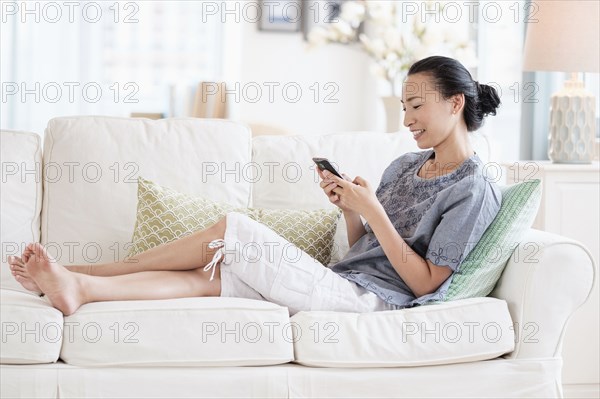 Japanese woman using cell phone on sofa