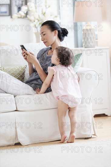 Mother and baby daughter using cell phone