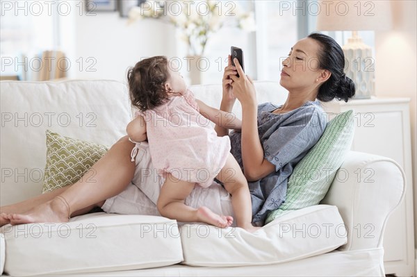 Mother photographing baby daughter