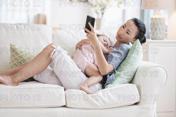 Mother and baby daughter using cell phone