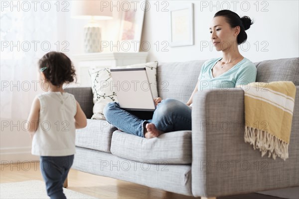 Mother using laptop ignoring baby daughter