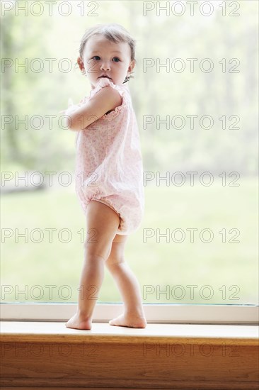 Mixed race girl standing at window