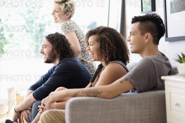 Friends watching television on sofa