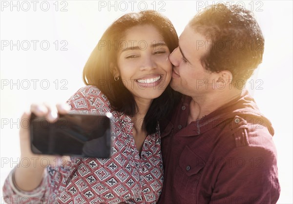 Hispanic couple taking selfie outdoors