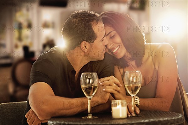 Hispanic couple holding hands at restaurant