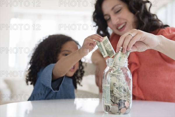 Mother and daughter saving money in jar