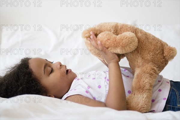 Mixed race girl playing with teddy bear