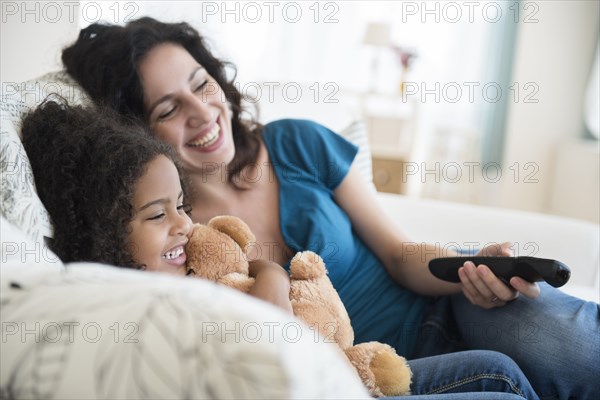 Mother and daughter watching television on sofa