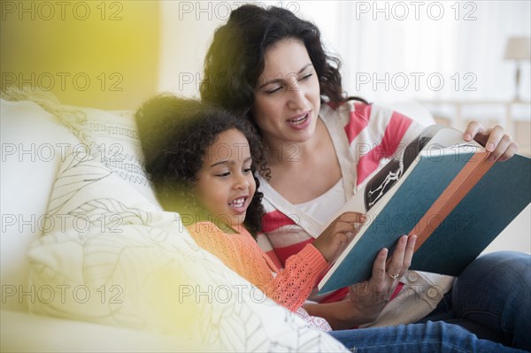 Mother and daughter reading on sofa