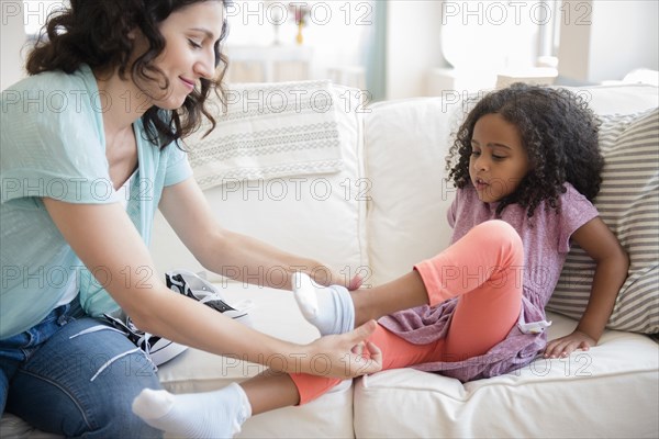 Mother helping daughter put on socks