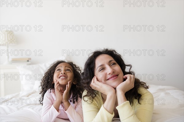 Mother and daughter daydreaming on bed