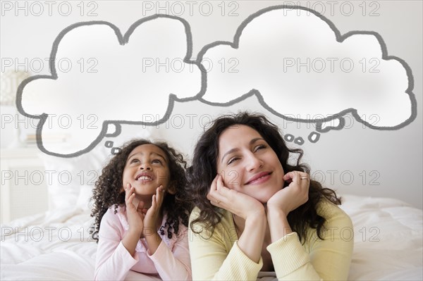 Mother and daughter thinking on bed