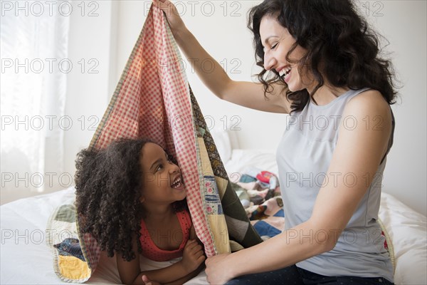 Mother and daughter playing in blanket fort